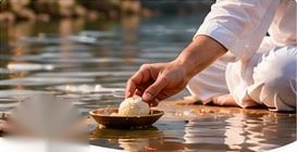 Person offering pind daan rice on the river bank